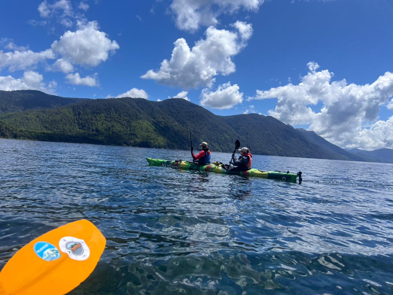 Kayak de travesía en lago del sur de Chile con montañas de fondo